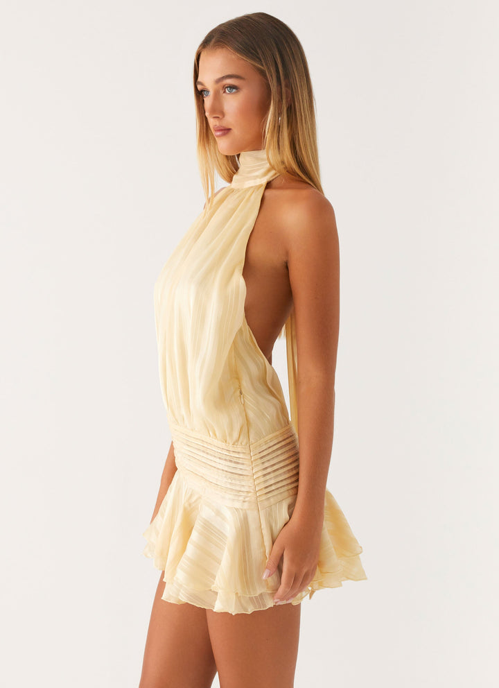Side view of cream halter mini dress showing open back and ruffled skirt layers