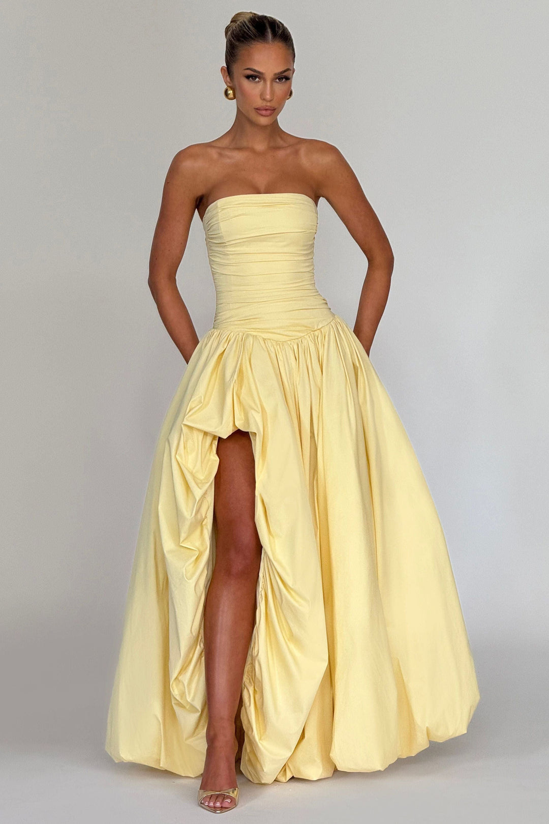 Full-length yellow strapless dress with ruched detailing and high-low hem