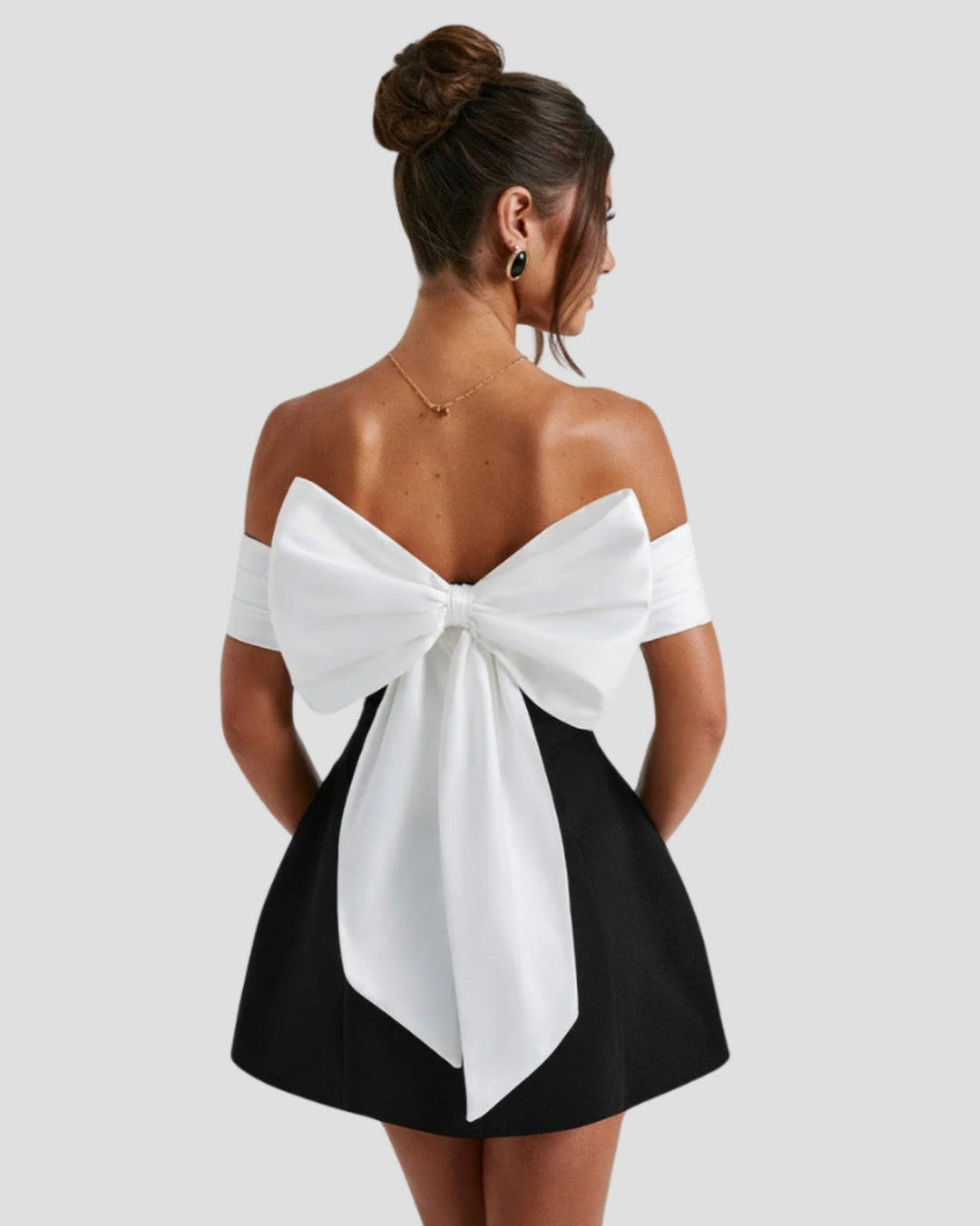 Back view of mini dress featuring dramatic white bow detail and off-shoulder design