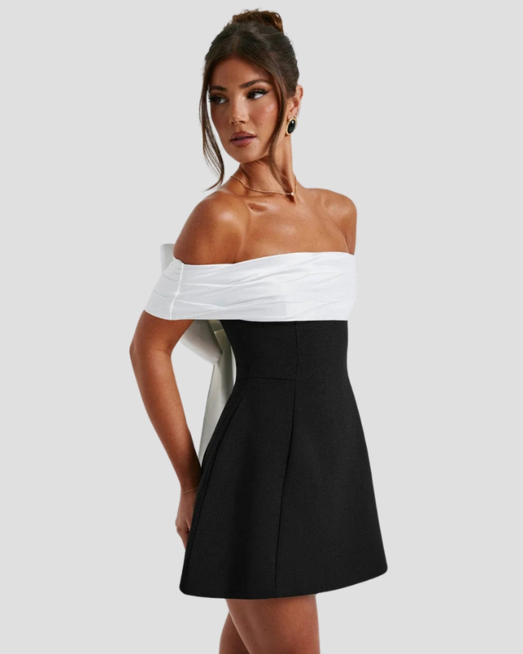 Side profile of black mini dress with structured A-line skirt and off-shoulder top
