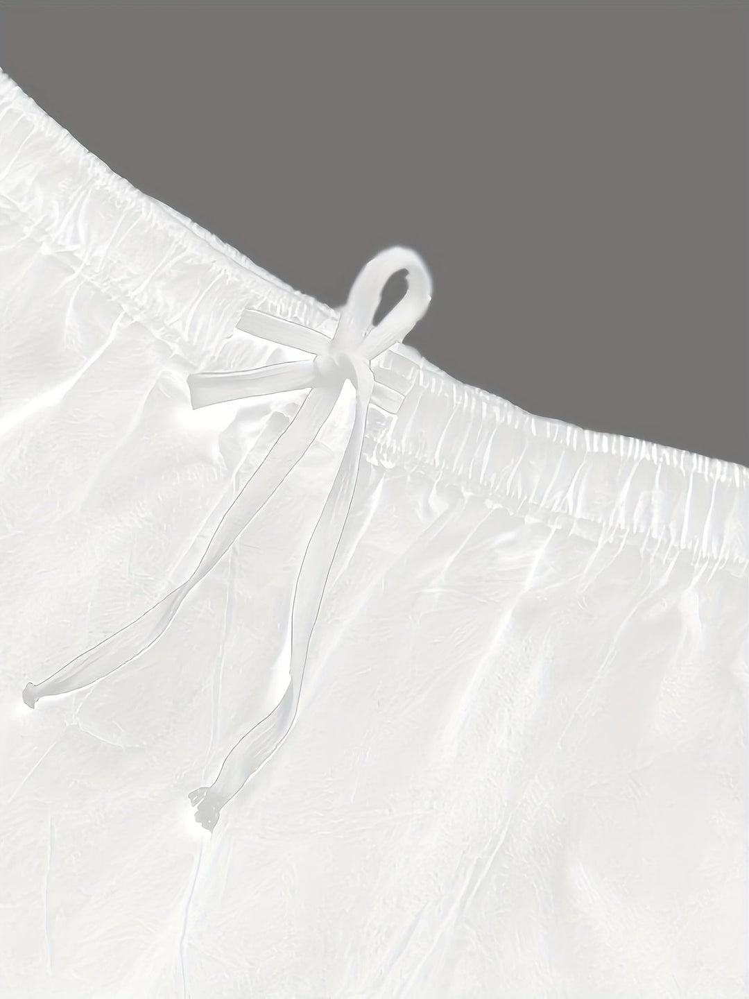Close-up of white swim shorts drawstring and waistband detail, men bathing suit fabric