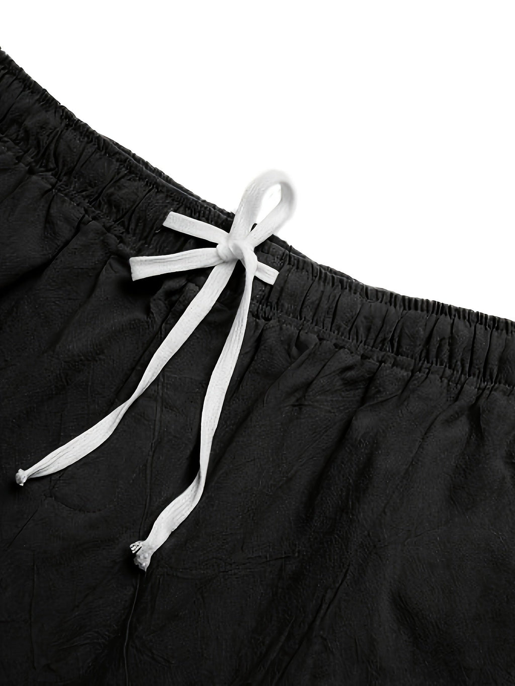 Close-up of black swim shorts waist with white drawstring tie and elastic waistband