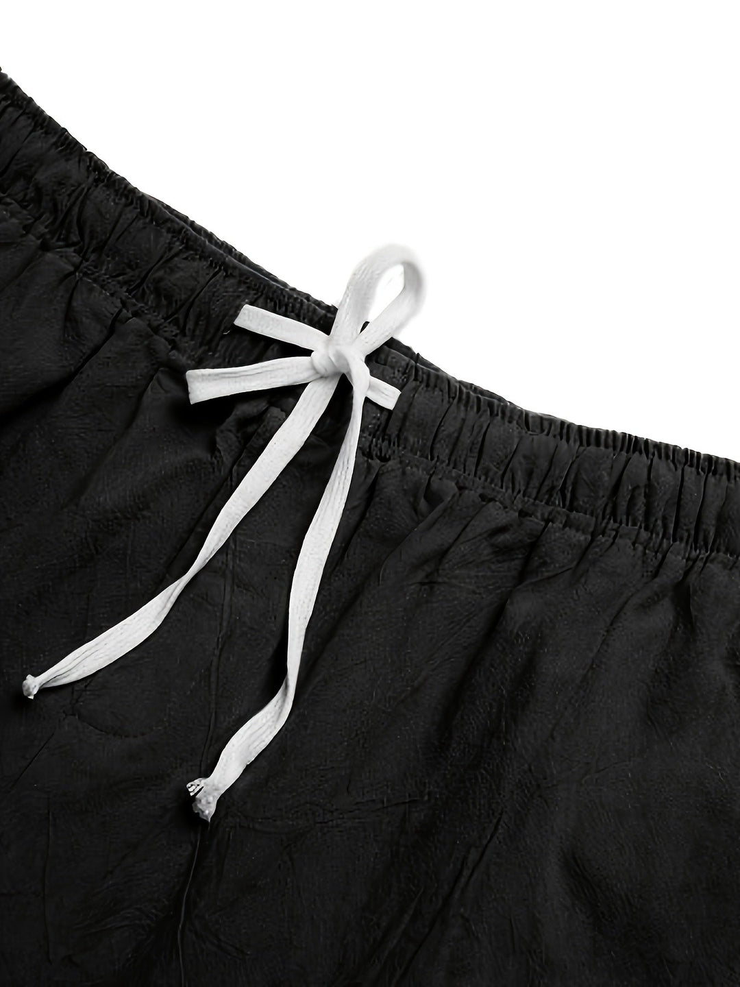 Close-up of black swim shorts waist with white drawstring tie and elastic waistband