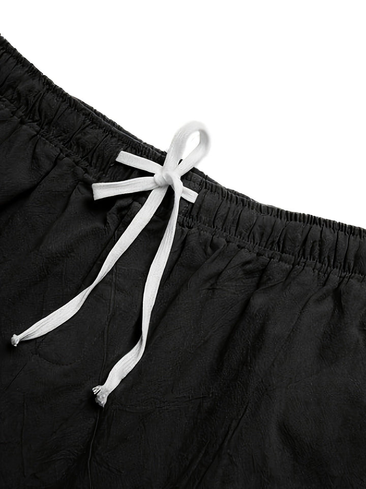 Close-up of black swim shorts waist with white drawstring tie and elastic waistband