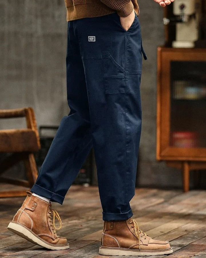 Tan workwear cargo pants with straight leg fit, utility pocket, and backpack accessory