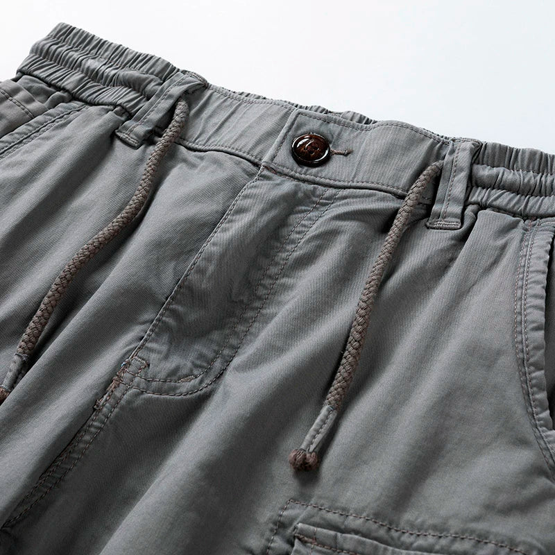 Close-up of gray cargo shorts drawstring waist and front pocket detail, showing casual utility style