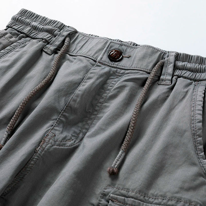 Close-up of gray cargo shorts drawstring waist and front pocket detail, showing casual utility style