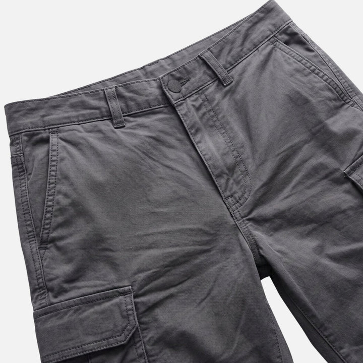 Close-up of dark gray cargo shorts waistband and front pocket details, men's shorts