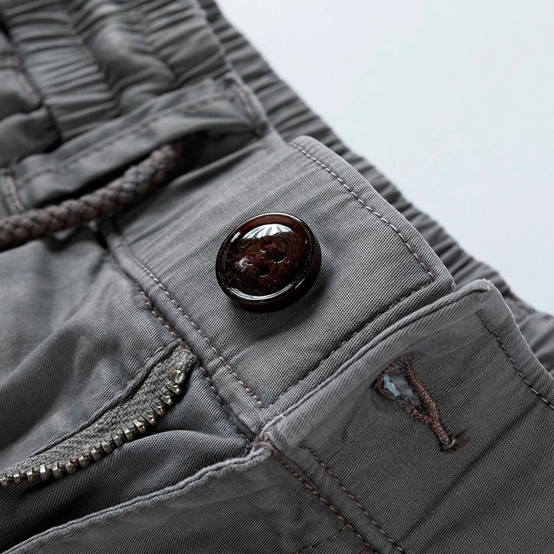 Close-up of gray men cargo shorts with pockets, showing button, zipper, and waistband detail