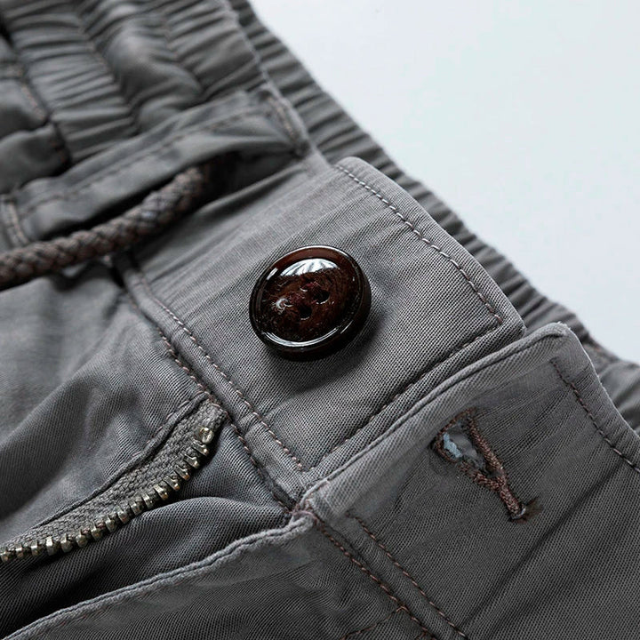 Close-up of gray men cargo shorts with pockets, showing button, zipper, and waistband detail