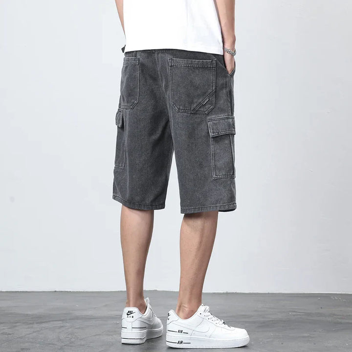 Back view of dark denim cargo shorts with knee length cut and utility pockets