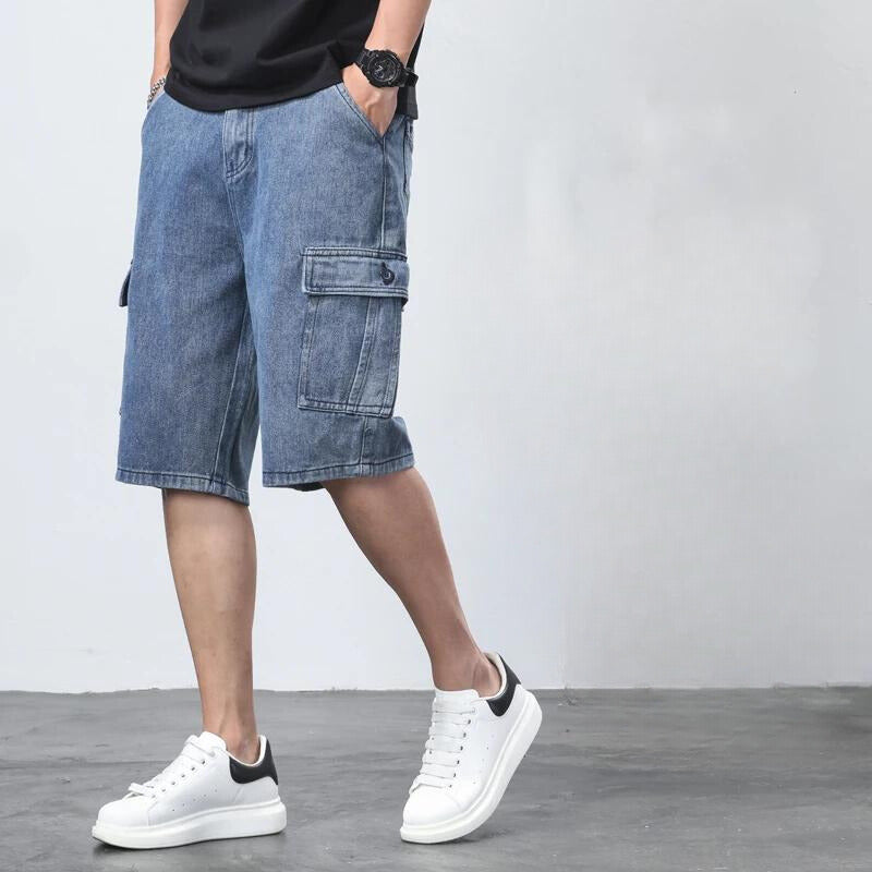 Blue denim cargo shorts for men shown at an angle with side pocket detail and white sneakers