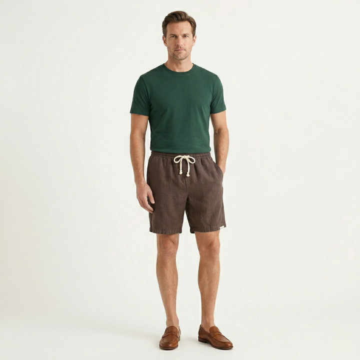 Men brown linen beach shorts worn with green t shirt and loafers, full view