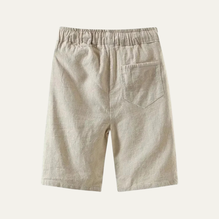 Back view of beige linen knee length shorts with elastic waist and patch pocket