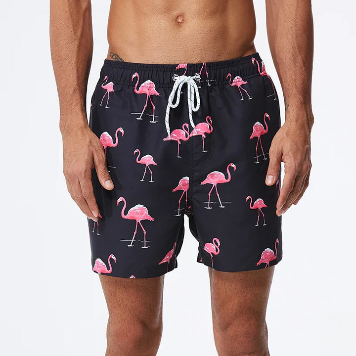Black swim shorts with pink flamingo print, side pockets and white drawstring waist