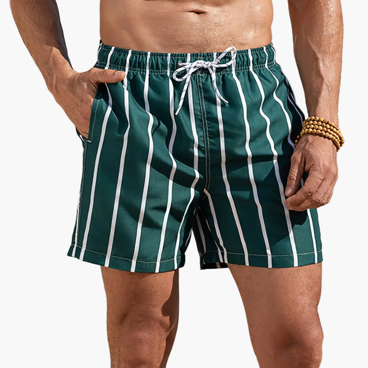 Product view of men striped swim shorts with pockets, dark green and white vertical stripes