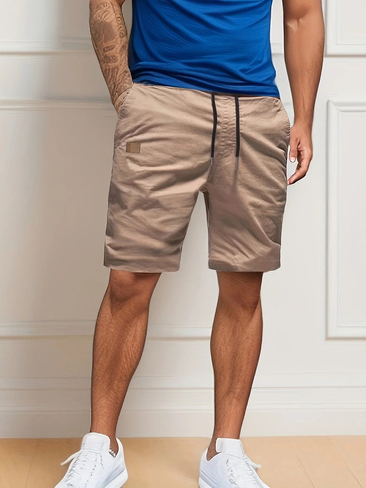 Tan men's summer cargo shorts with elastic waistband, drawstring, and casual knee-length style