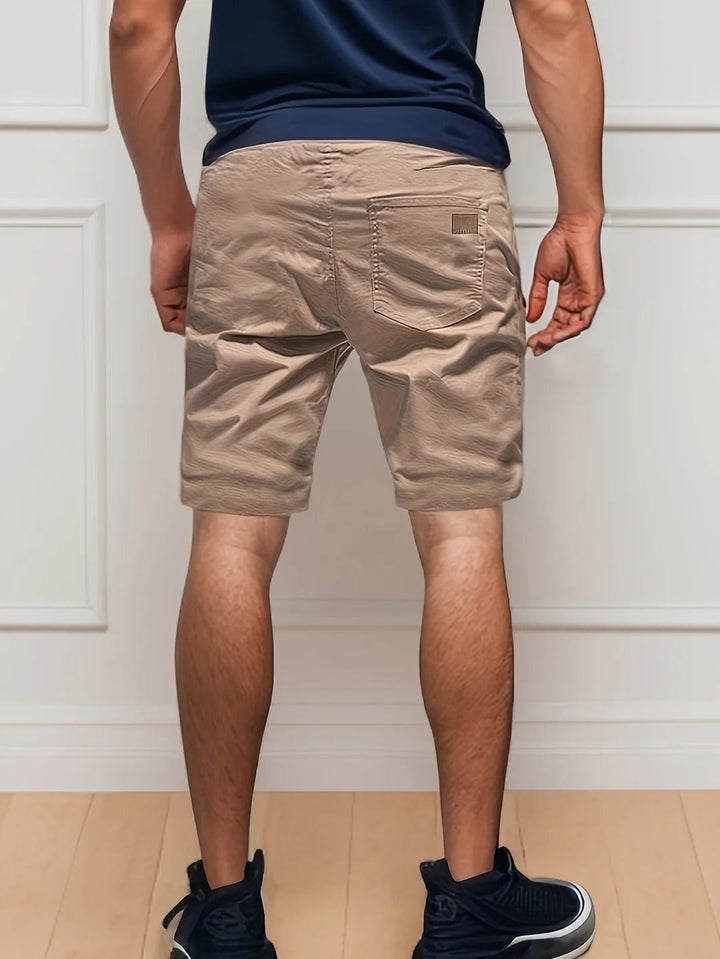 Back view of tan men's cargo shorts with elastic waist, rear pocket, and casual summer style