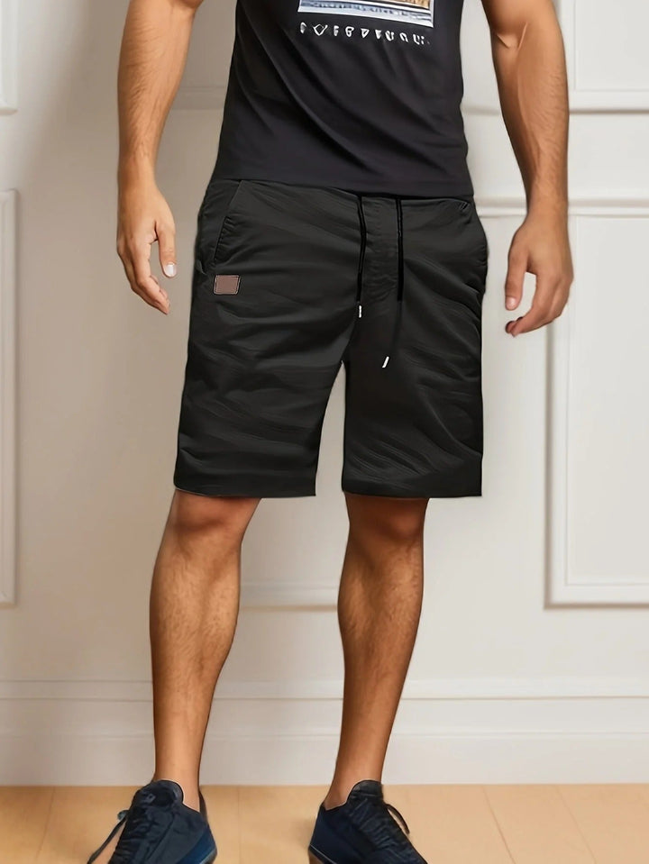 Black men's cargo shorts with elastic waist, drawstring, side pocket, and knee-length fit