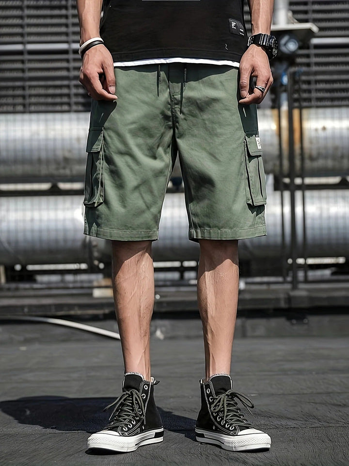 Olive green men summer cargo shorts with flap pockets and relaxed fit, worn with black high-top sneakers
