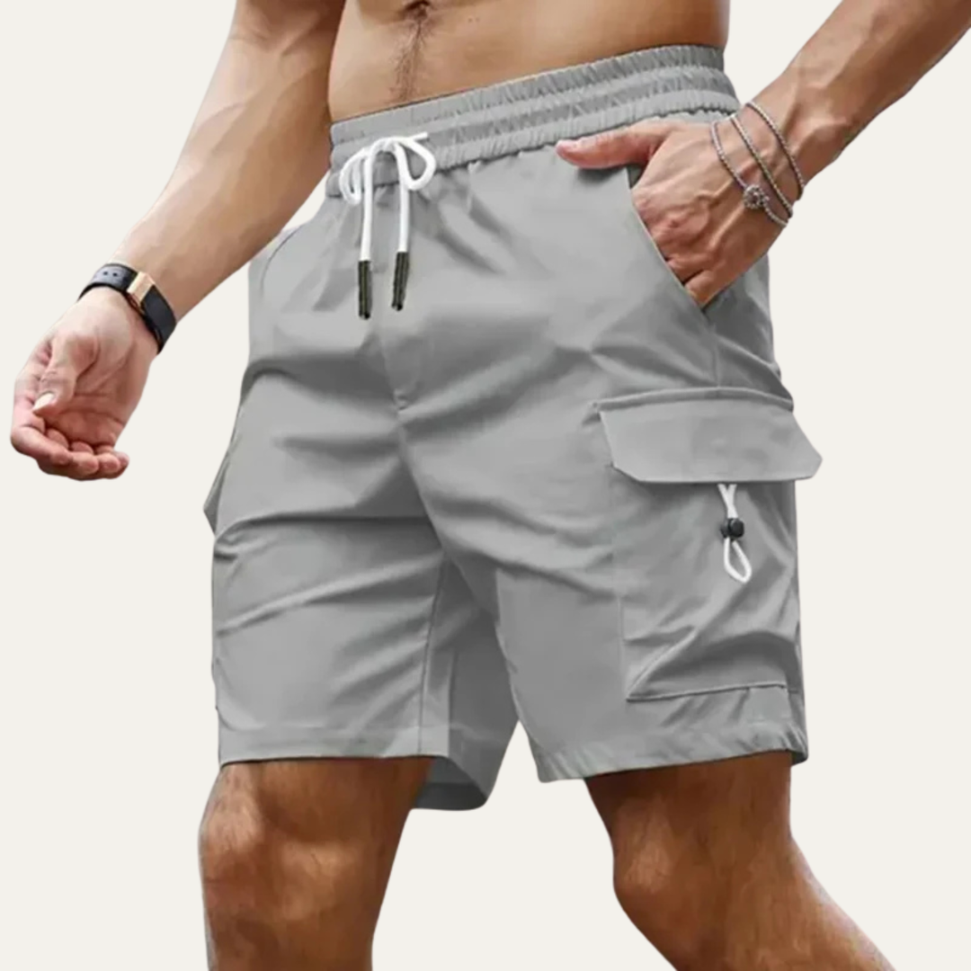 Model wearing light gray cargo shorts with pockets and drawstring waist in a summer shorts style