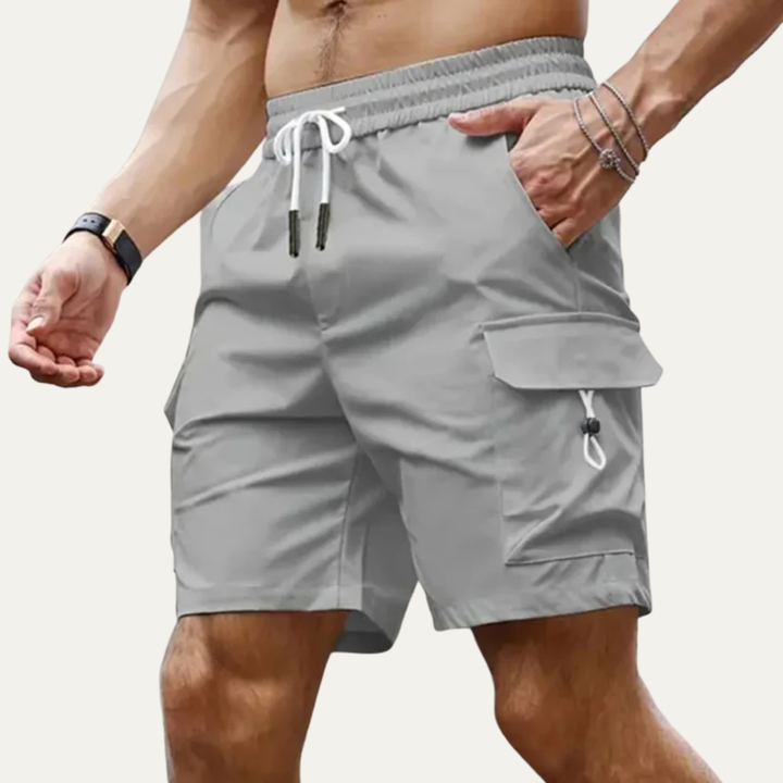 Model wearing light gray cargo shorts with pockets and drawstring waist in a summer shorts style