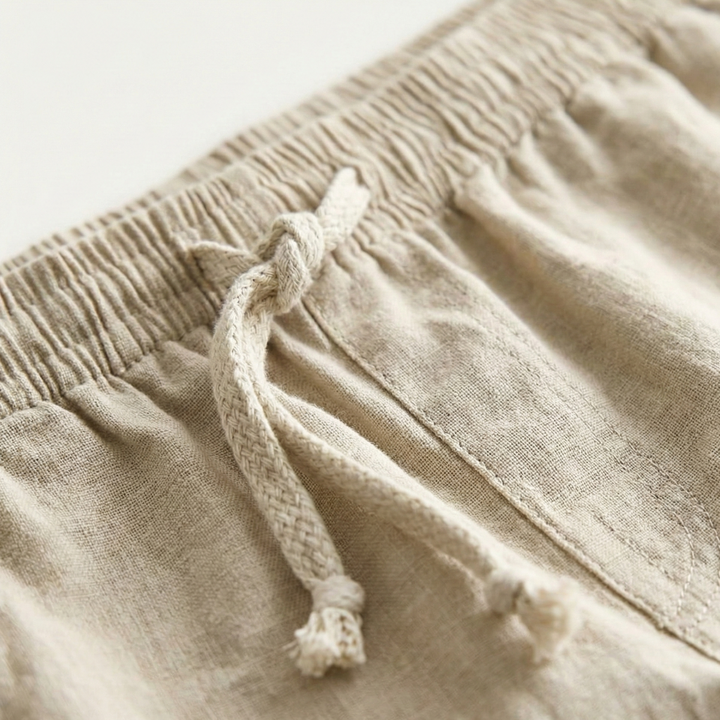 Close-up of beige linen shorts waistband with braided drawstring and gathered elastic waist