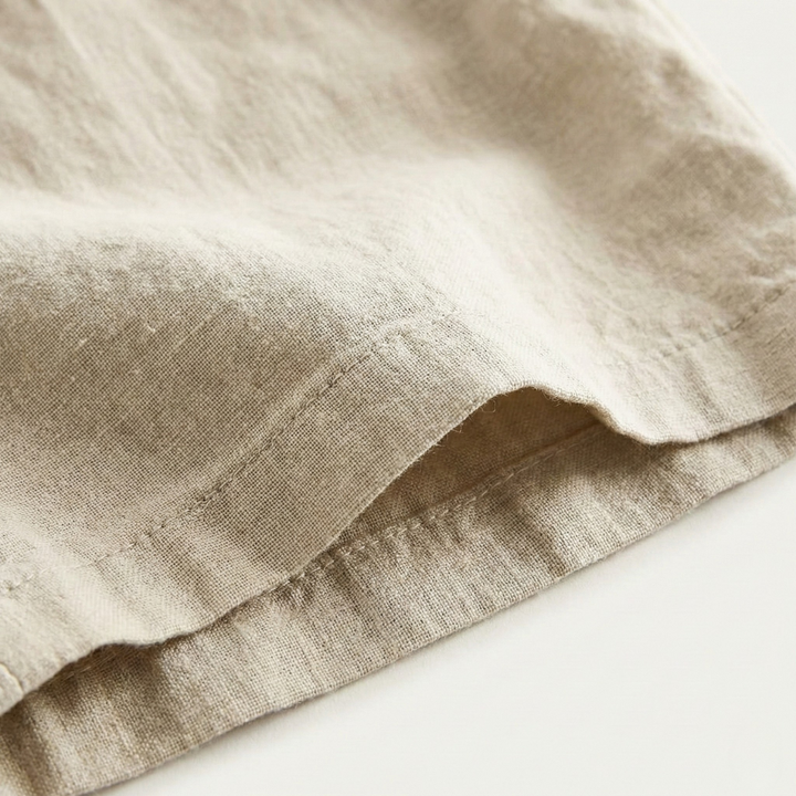 Close-up of beige men's linen shorts hem showing lightweight fabric and stitched edge