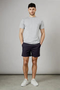 Full body outfit showing navy tailored shorts for men with side pockets and mid-thigh length