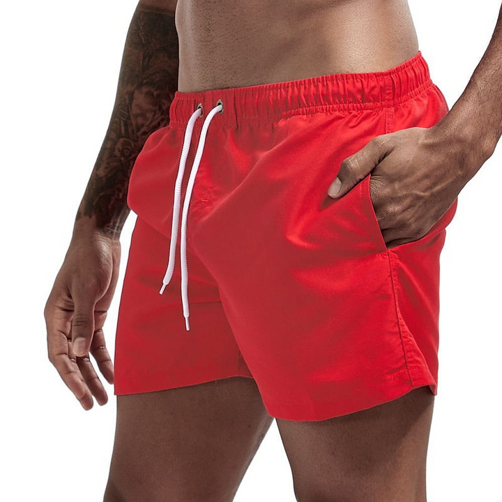 Red men swim shorts with elastic waistband, drawstring, and side pocket, front product view