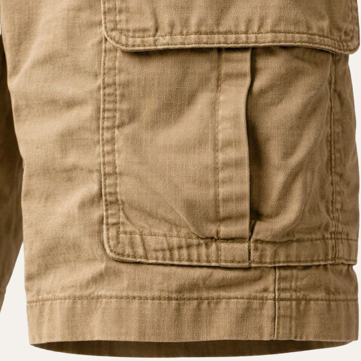 Side pocket detail on khaki tactical cargo shorts with stitched flap pocket