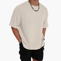 Beige textured crew neck short sleeve t-shirt with relaxed fit, model wearing black shorts
