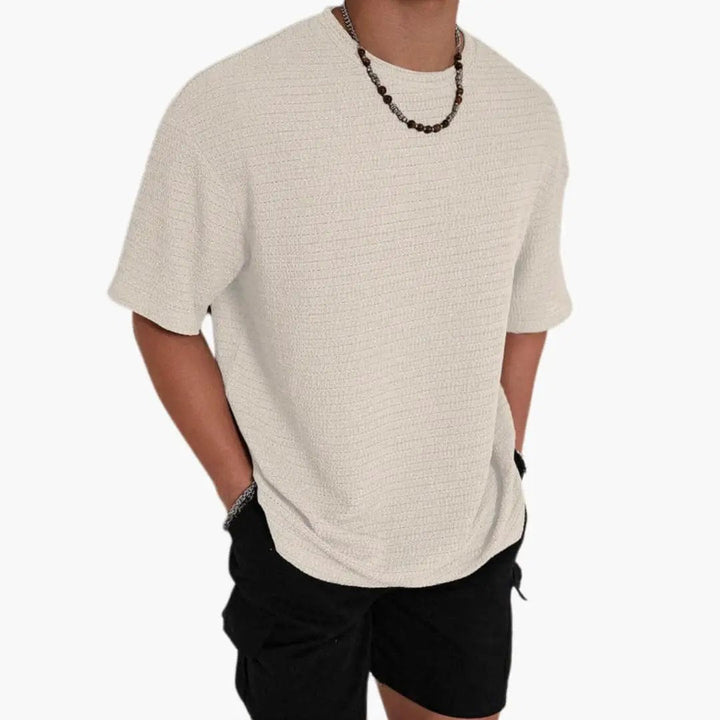 Beige textured crew neck short sleeve t-shirt with relaxed fit, model wearing black shorts