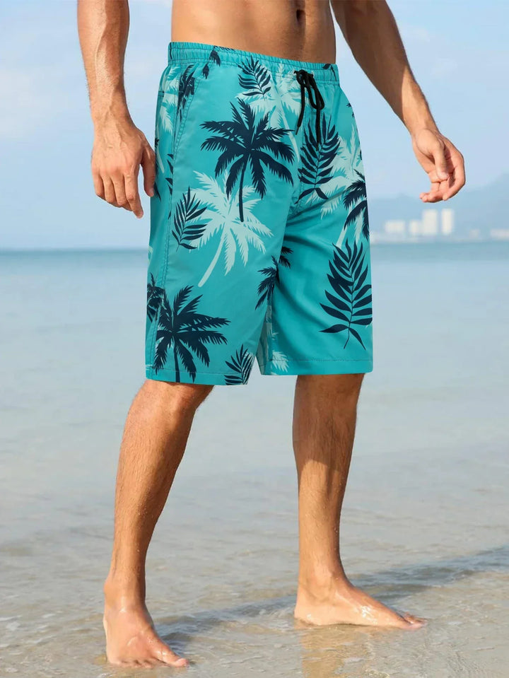 Men's beach swim shorts in turquoise with palm print, drawstring waist, worn at the shoreline