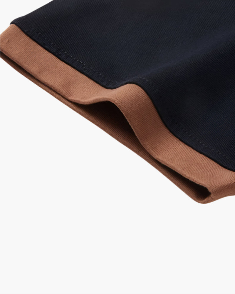 Close-up of black polo shirt sleeve with brown contrast cuff and stitched hem detail