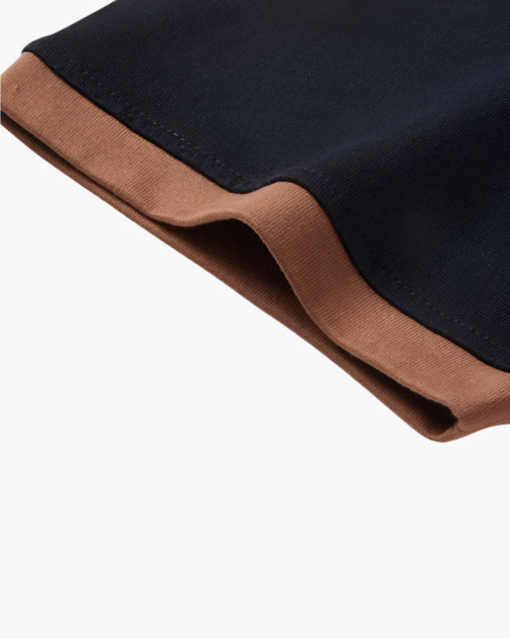 Close-up of black polo shirt sleeve with brown contrast cuff and stitched hem detail