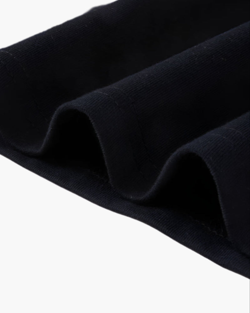 Close-up of black polo shirt sleeve hem showing brown contrast trim and soft knit fabric