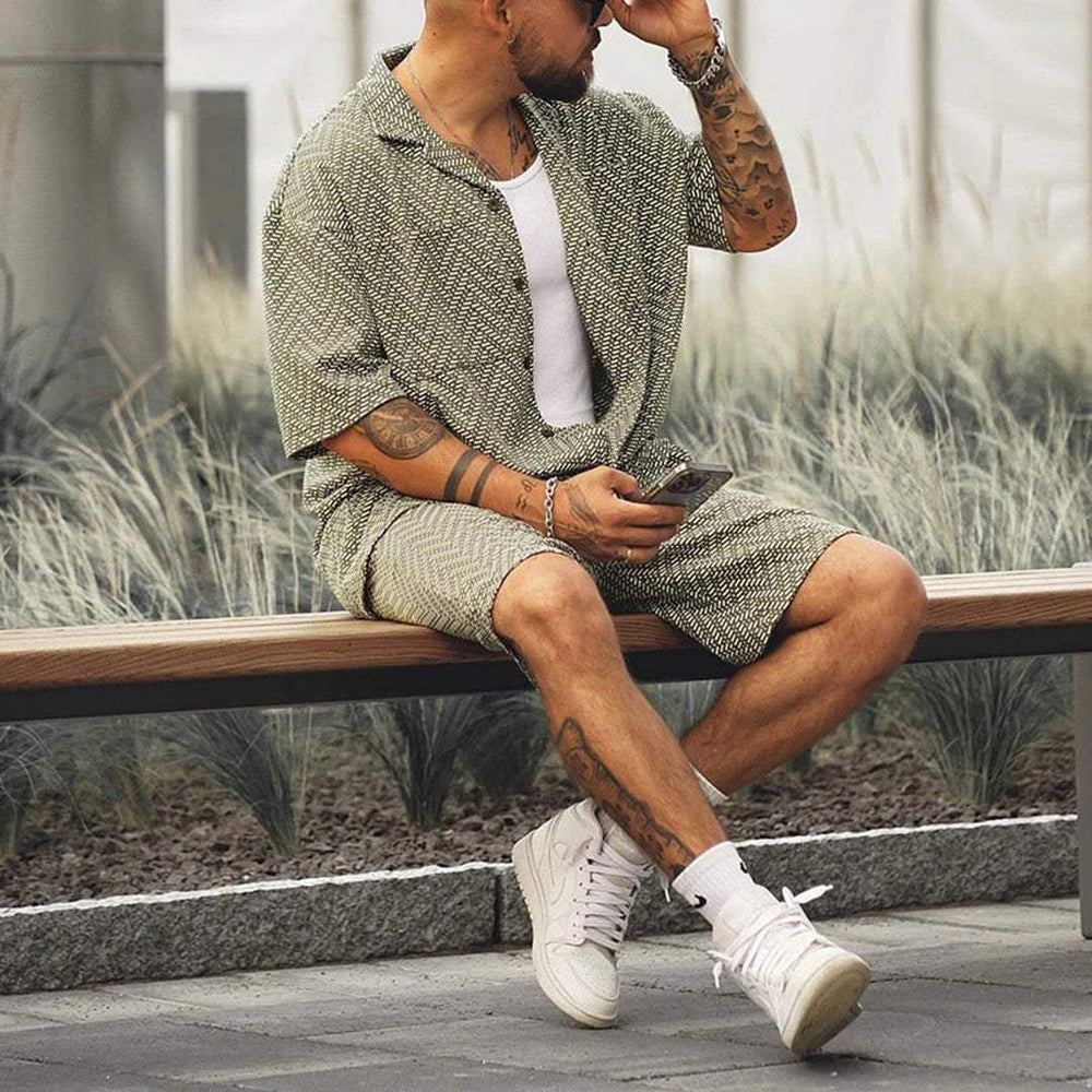 Green patterned short sleeve shirt and shorts set worn seated with casual summer styling