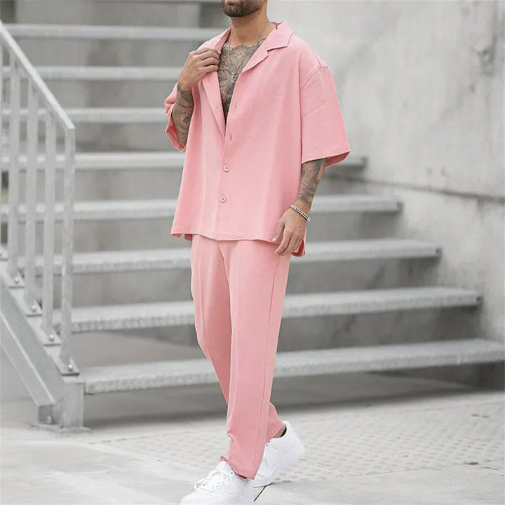 Men's pink casual two piece set with short sleeve shirt, open collar, and matching trousers