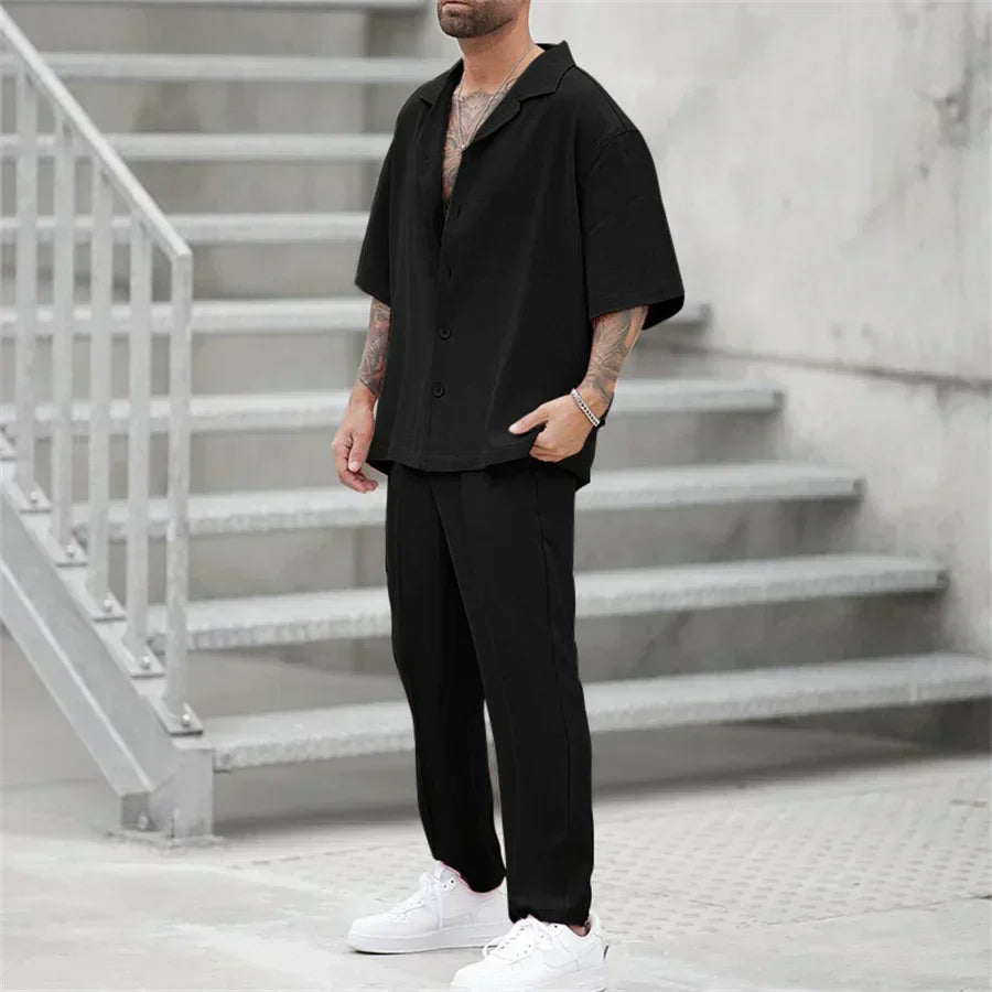Men's black short sleeve shirt and pants set with relaxed fit, shown in a full length view