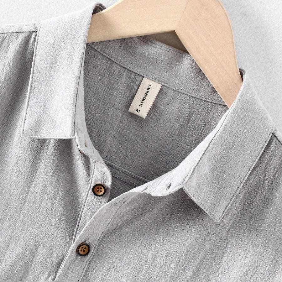 Close-up of light gray linen shirt collar, buttons, and textured fabric detail