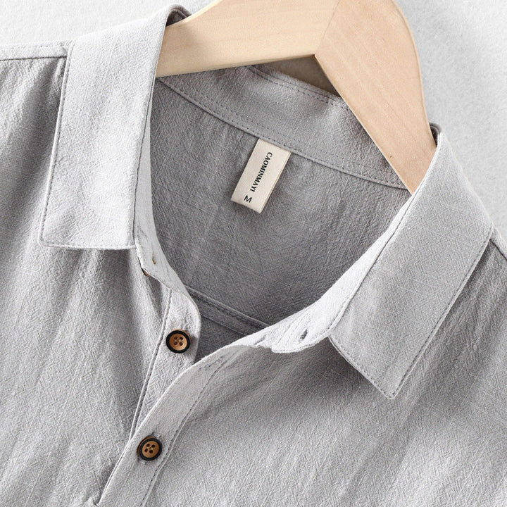 Close-up of light gray linen shirt collar, buttons, and textured fabric detail
