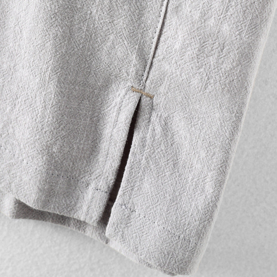 Close-up of light gray men's linen shirt hem with side slit and stitched edge