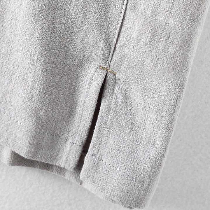 Close-up of light gray men's linen shirt hem with side slit and stitched edge