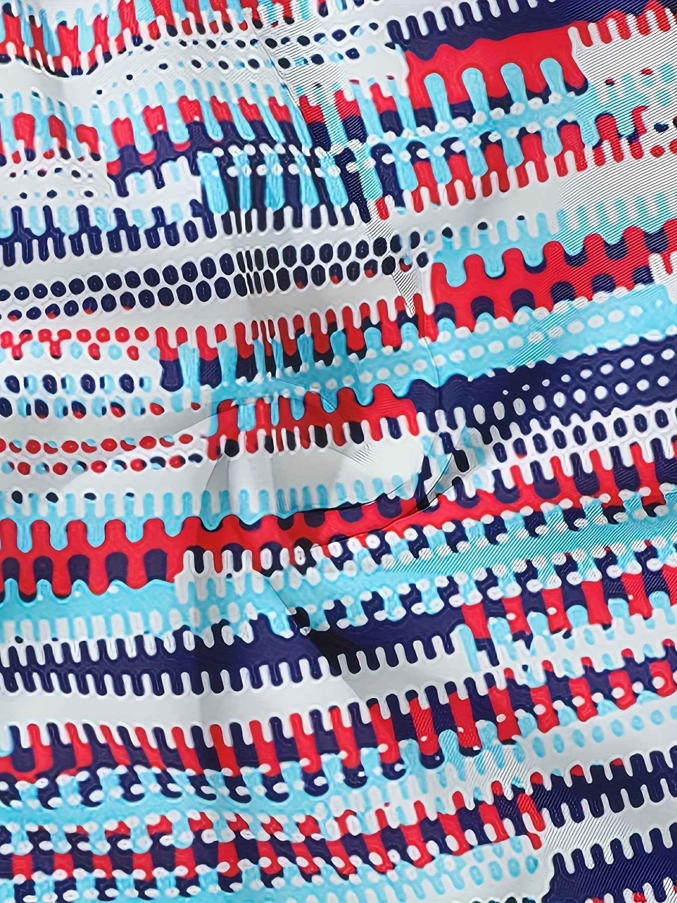 Close-up of men's graphic swim shorts fabric with textured striped pattern in blue, red, white, and navy