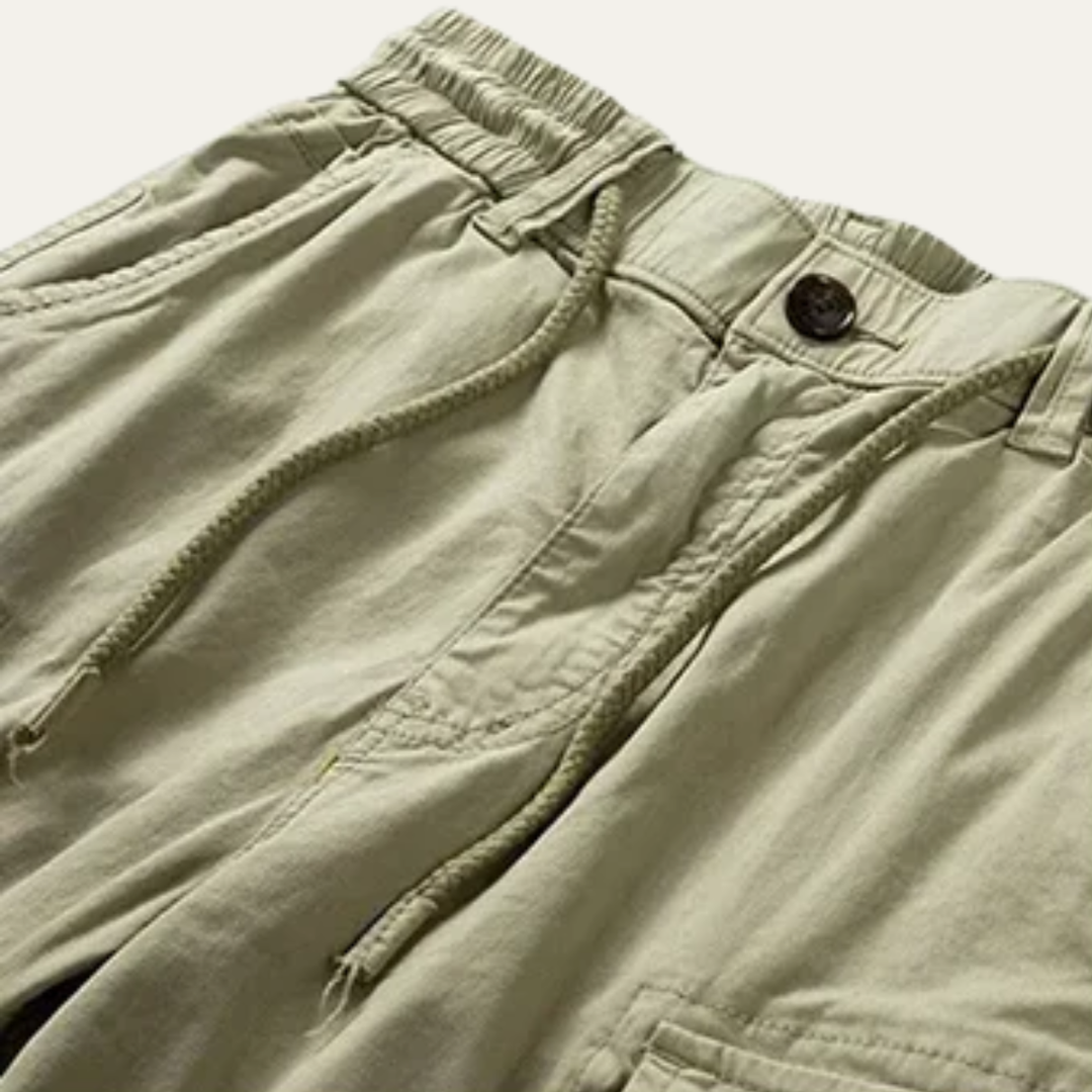 Close-up of khaki cargo shorts waistband with drawstring, button closure, and front pocket detail