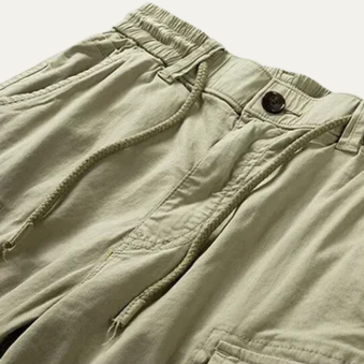 Close-up of khaki cargo shorts waistband with drawstring, button closure, and front pocket detail