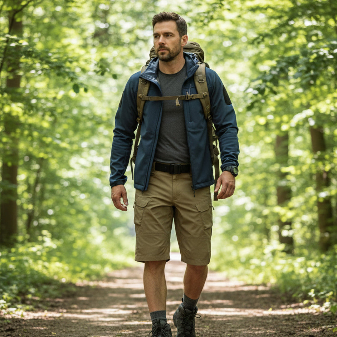 Khaki tactical cargo shorts with zip pockets shown on a hiker in a forest trail
