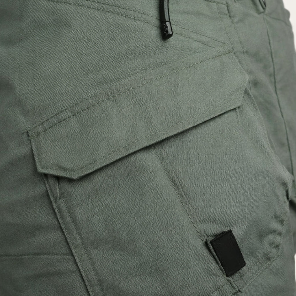 Close-up of olive cargo shorts side pocket with flap and zipper detail