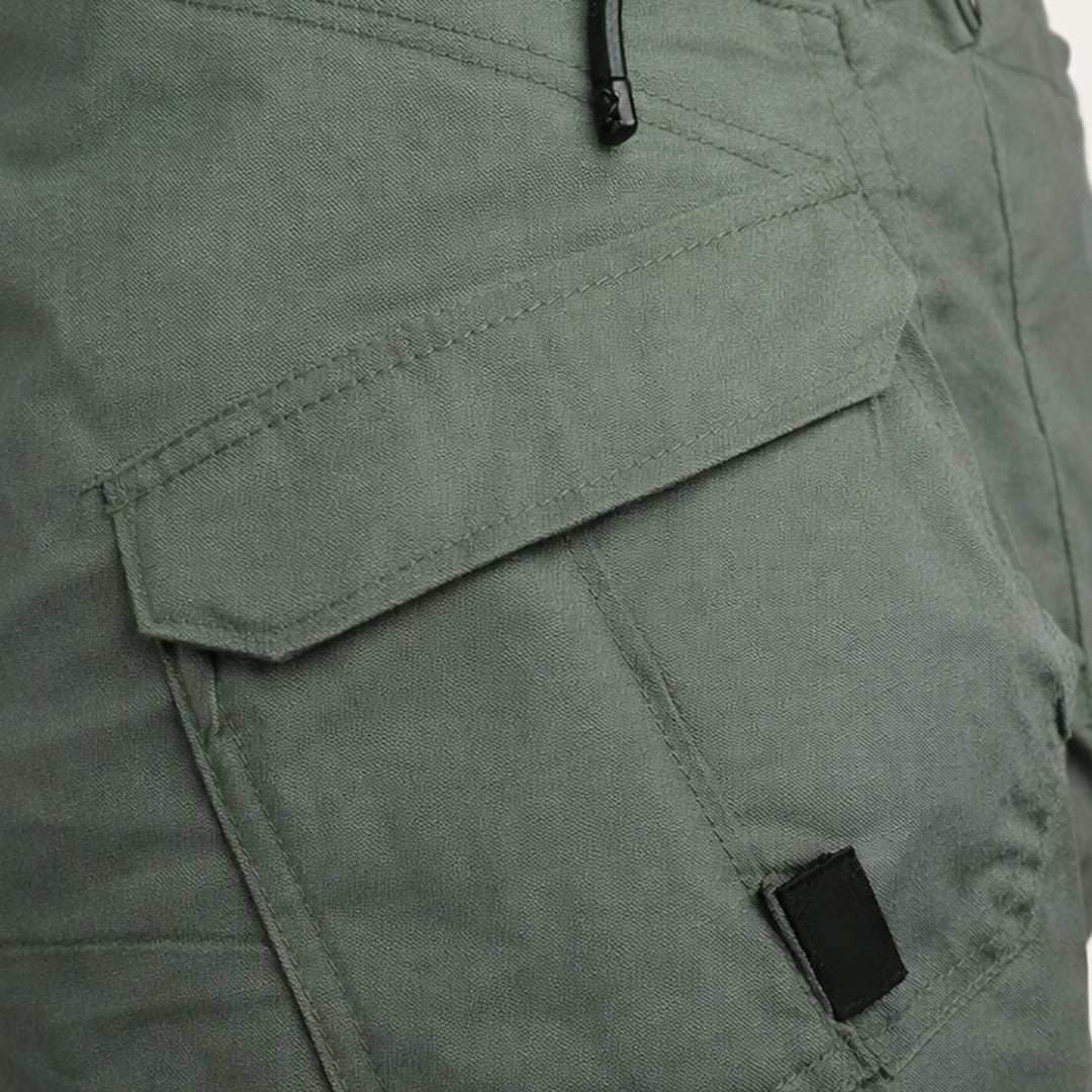 Close-up of olive cargo shorts side pocket with flap and zipper detail